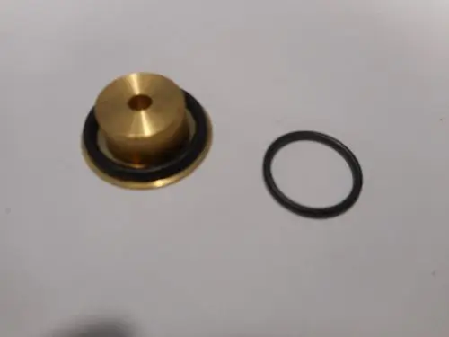 Düse mit metallischem Körper und Gummidichtung, geeignet für Anwendungen von Remeha, liegt neben einem schwarzen O-Ring auf einem weißen Hintergrund.